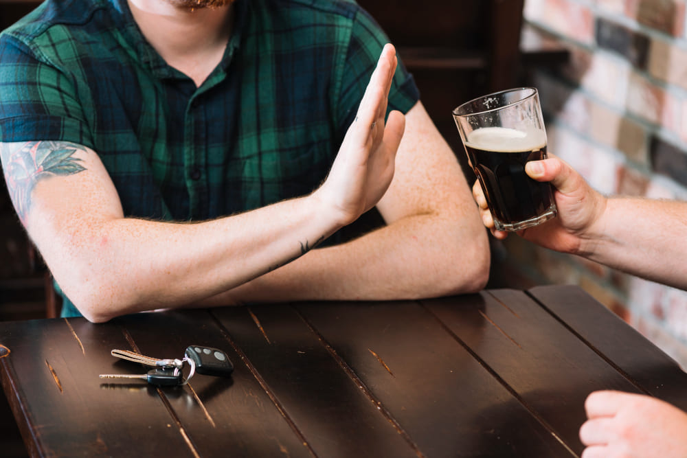 Man refusing beer with car keys on table