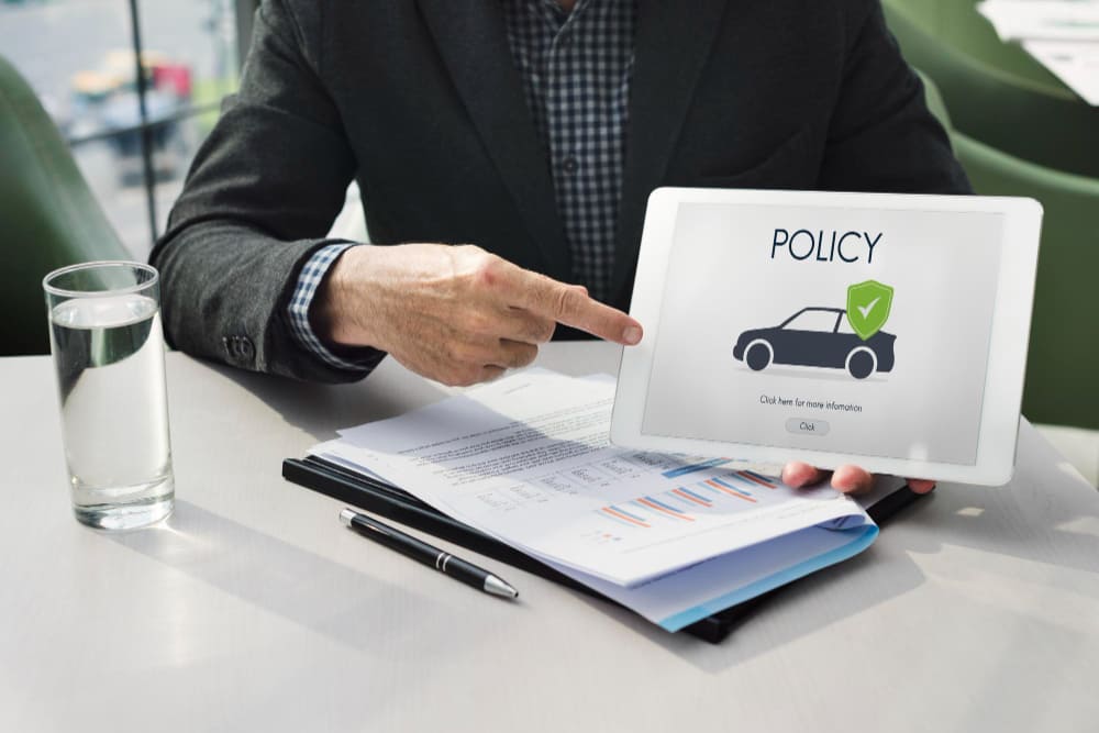 Person pointing at a tablet displaying a car insurance policy