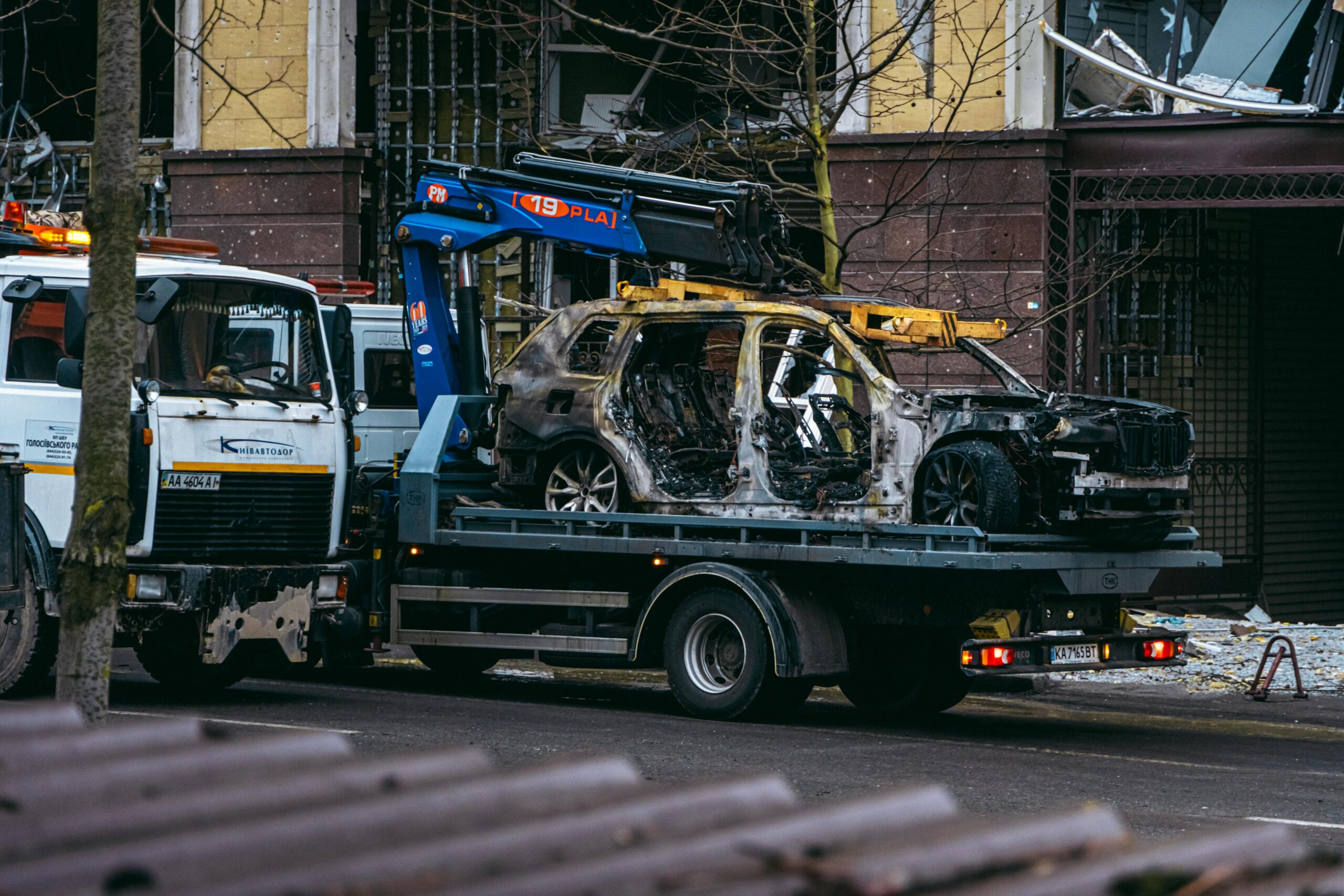Burned-out SUV loaded on a flatbed tow truck on a city street