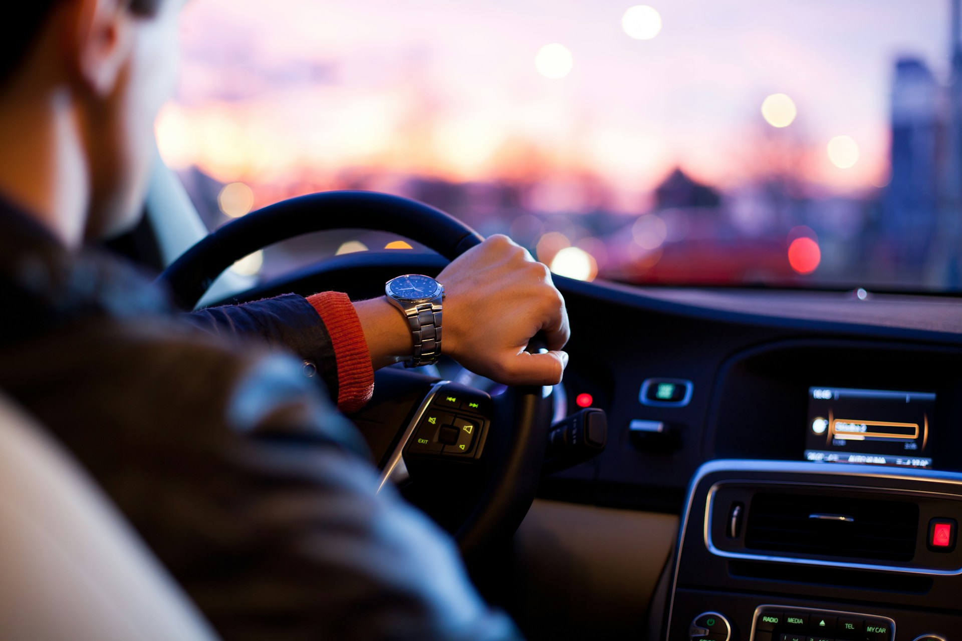 Driver Holding Steering Wheel During Evening Commute Close-up view from inside a car showing a driver’s hand