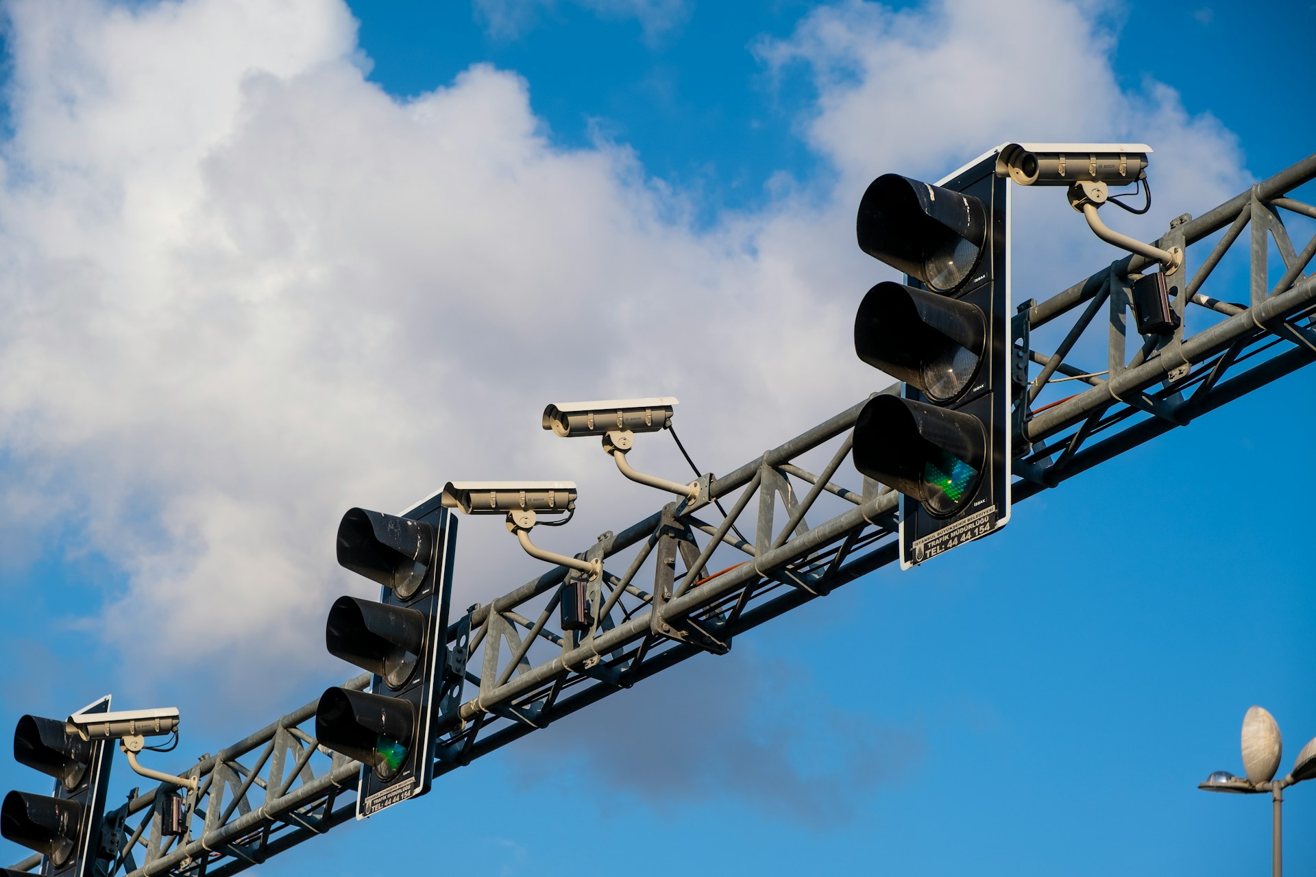 Traffic Lights and Surveillance Cameras Multiple traffic lights mounted on an overhead metal gantry